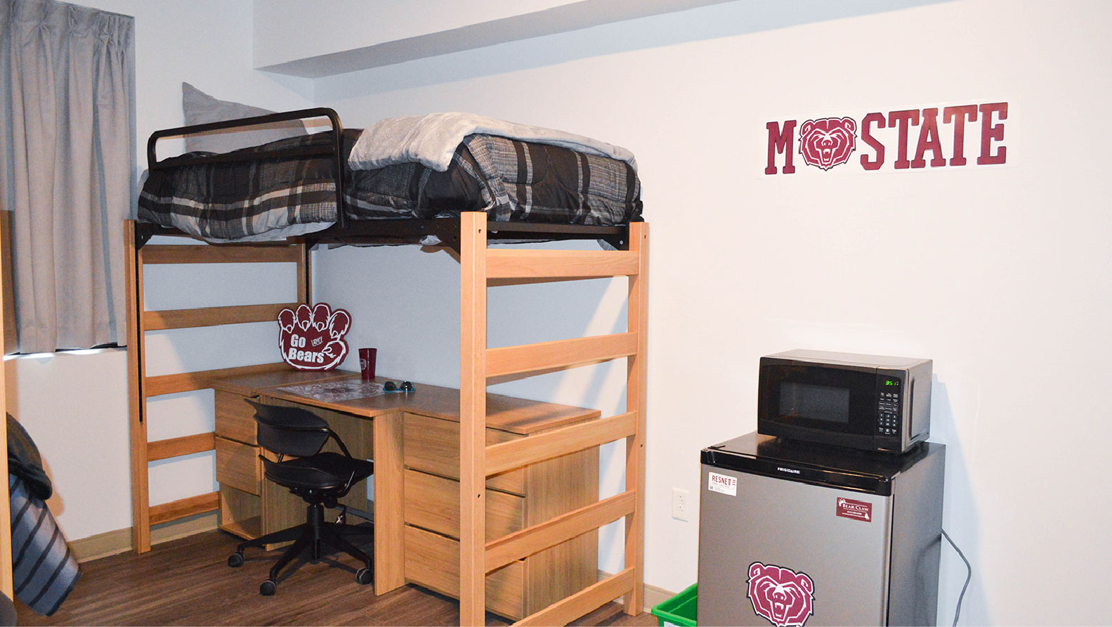 Heitz bedroom with lofted bed and desk with chair underneath and mini fridge and microwave beside