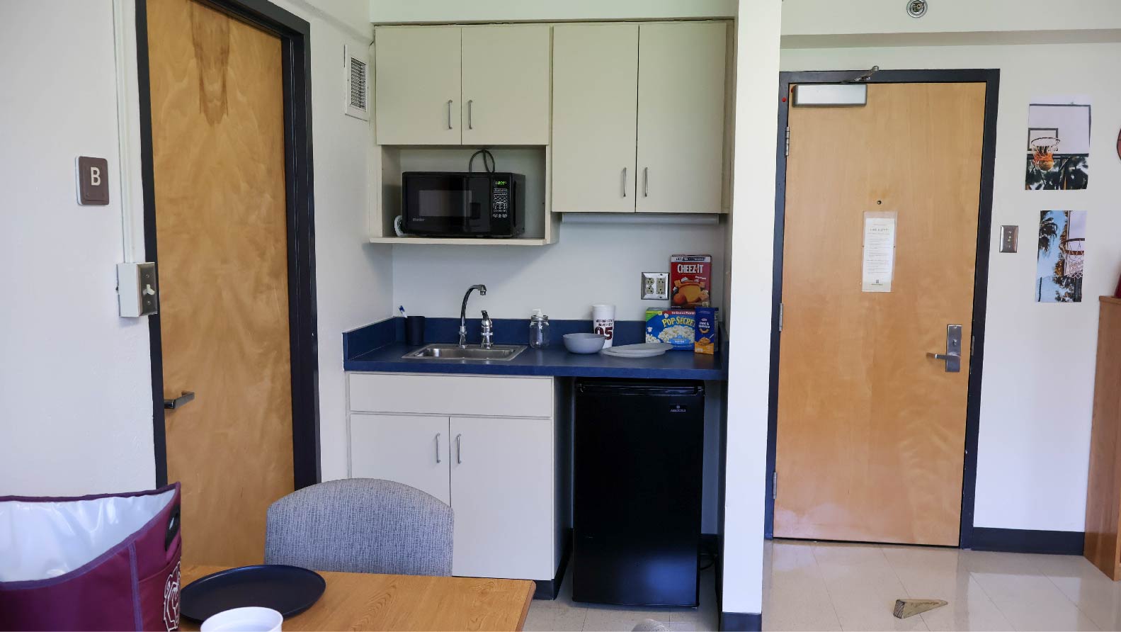kitchenette with upper and lower cabinets sink microwave and mid size fridge