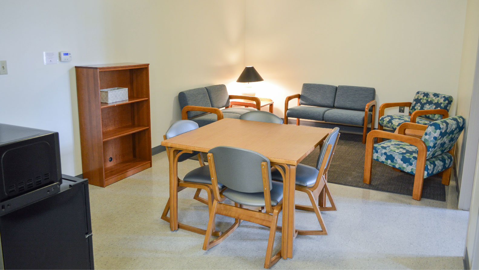 Scholars En-suite living area with 2 loveseats 2 chairs a dining table with 4 chairs and bookshelf