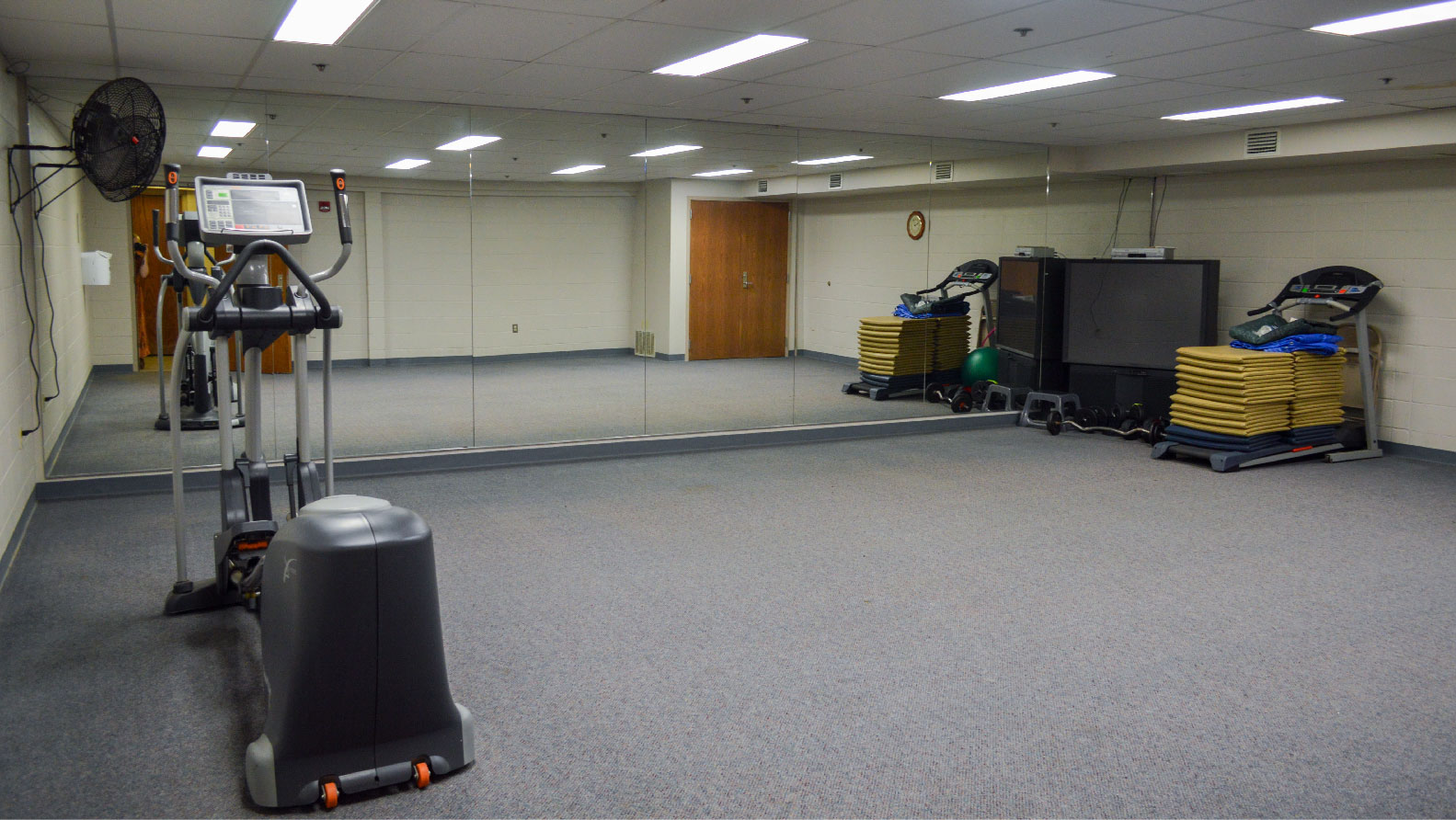 room with wall of mirrors elliptical machine and treadmill