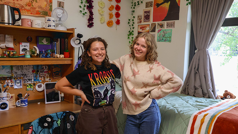 two students smiling standing in their room