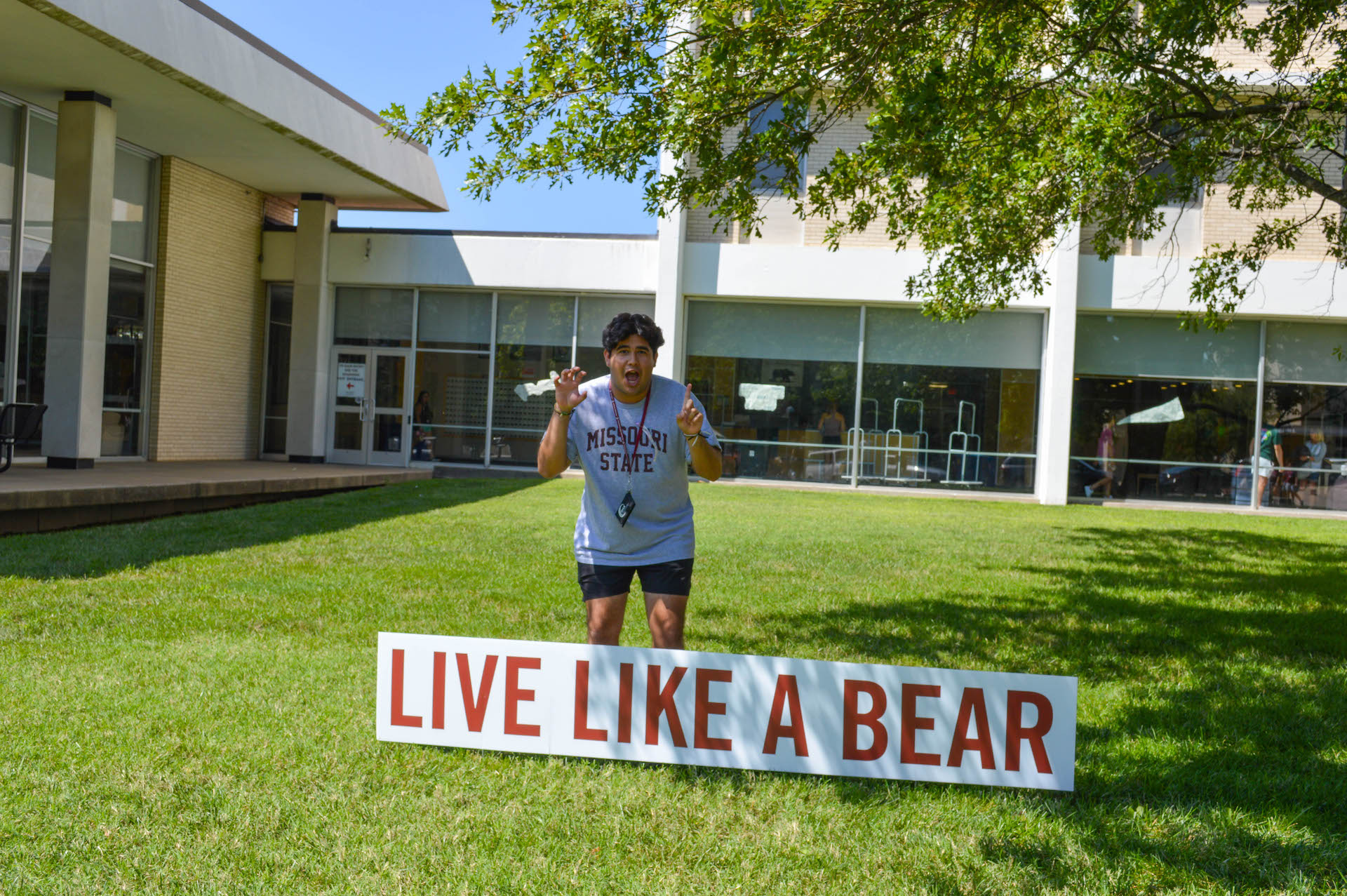 person smiling in front of Live Like a Bear sign
