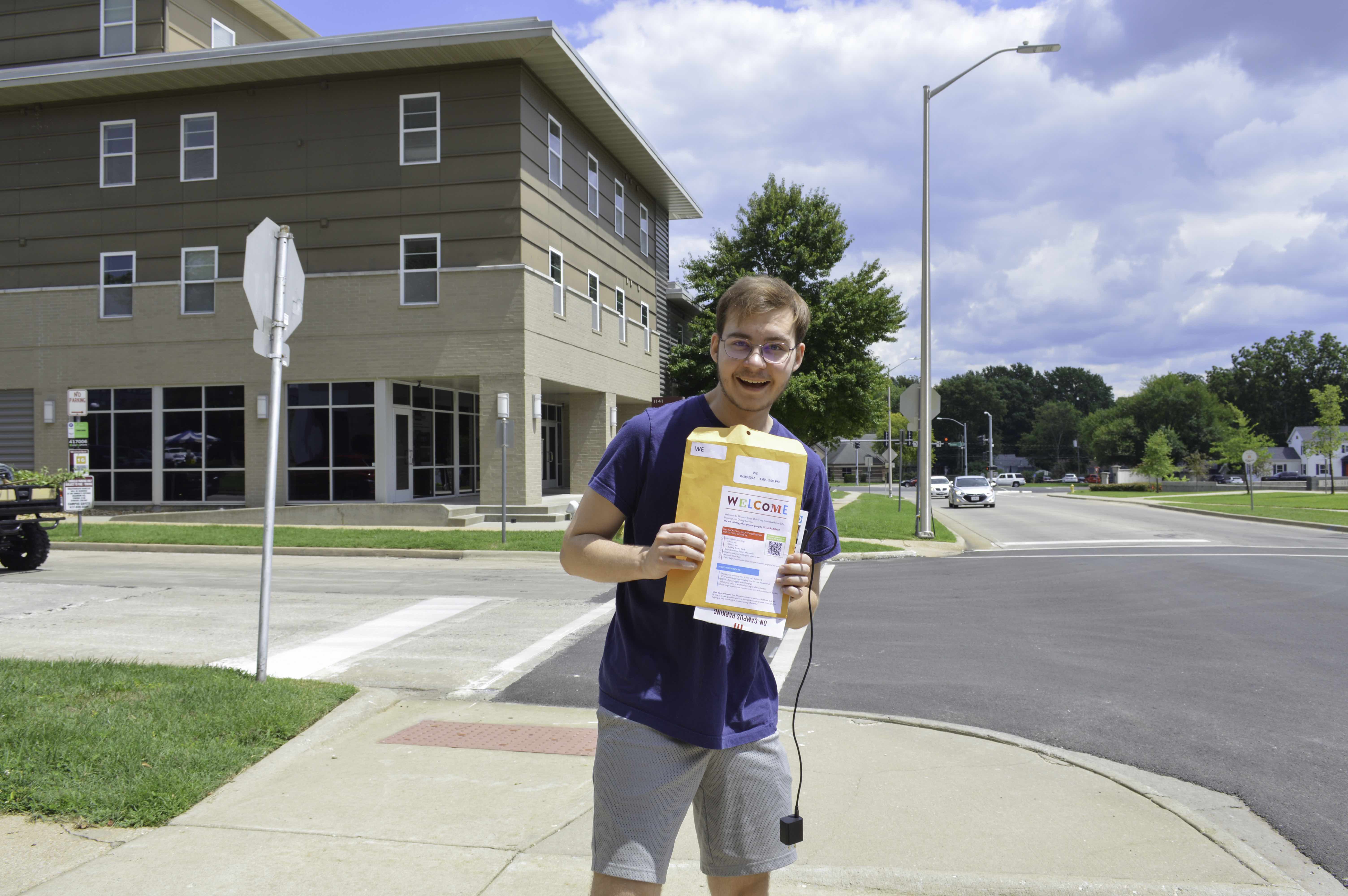 Student holding welcome packet and smiling