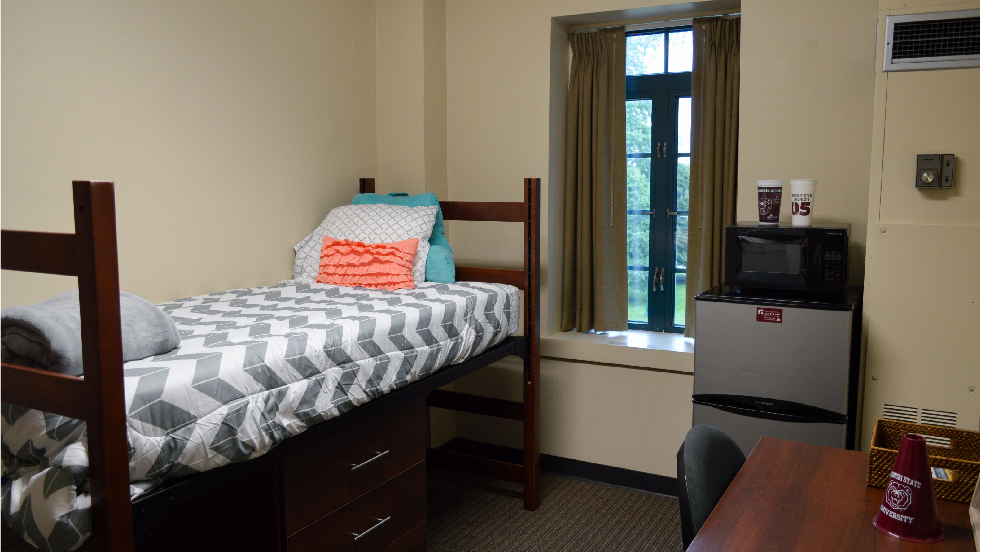 Room with bed fridge microwave and desk