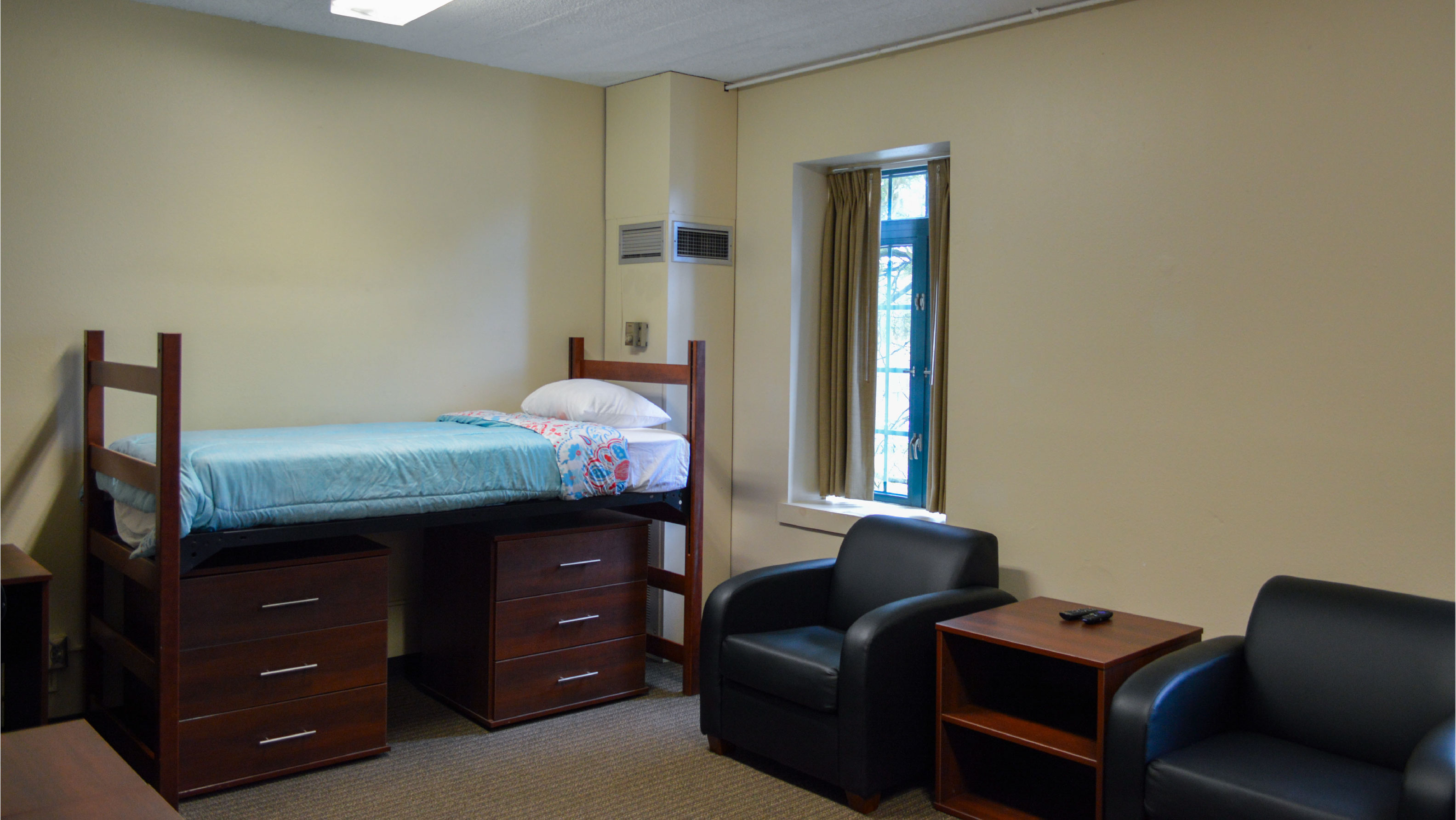 Bedroom with bed under-bed storage two armchairs and side table